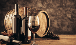 Copa de vino tinto con botella y barril de madera, ideal para bodegas y eventos.