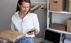 Mujer revisando código de barras en paquetes para envíos rápidos y precisos.