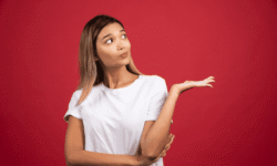 Etiqueta alt: Mujer con expresión curiosa señalando un espacio para información adicional.