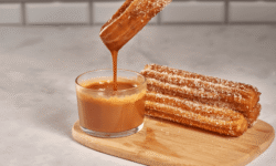 Churros cubiertos de azúcar y canela, con dulce de leche y una taza de café helado para disfrutar.